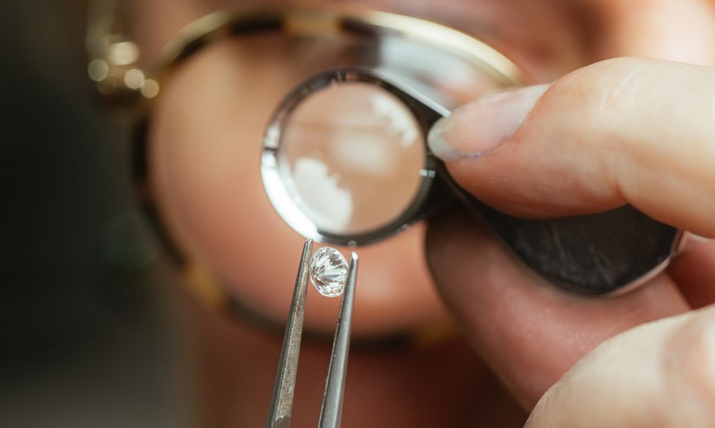 Guldsmed granskar en naturlig diamant med ett förstoringsglas.