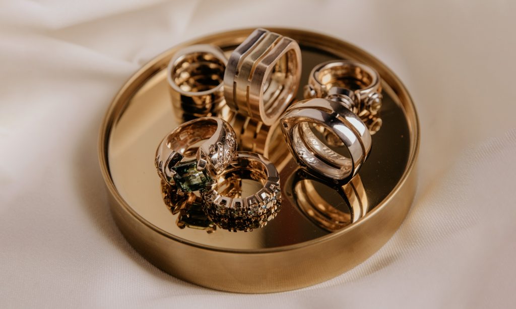 En skål i guld fylld med unika guldringar med ädla juveler.