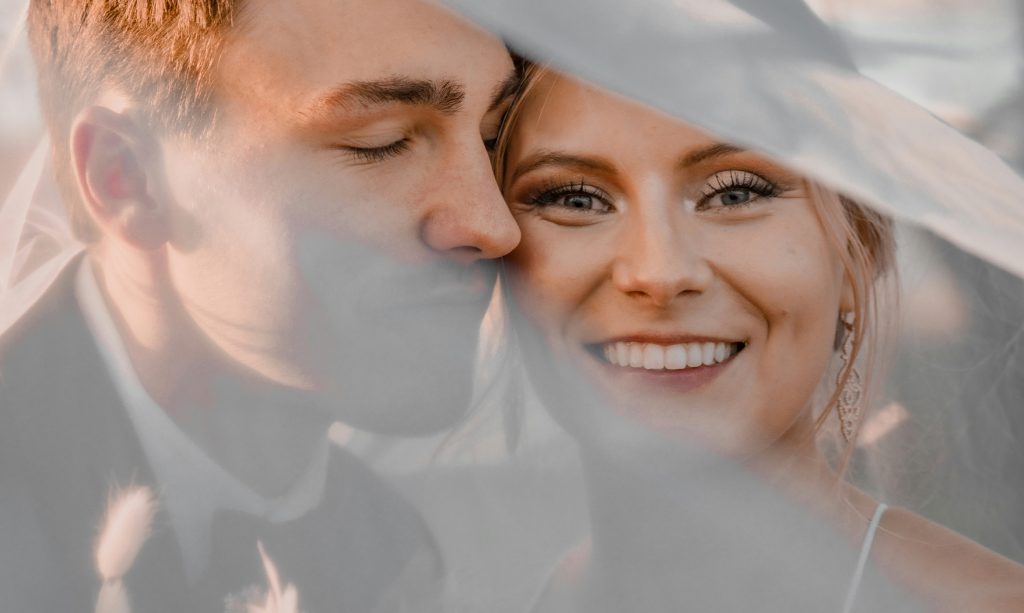 Nygift par i mjukt ljus under slöja – en varm och personlig känsla som speglar valet av vigselring